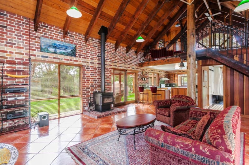 Open plan living area with lots of wood and brick work, and a wood burner fireplace at Chianti Cottages in Torquay Great Ocean Road.