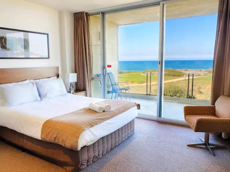 Guest room with bed and sliding doors leading to a balcony with views of the ocean at Wyndham Resort in Torquay Victoria.
