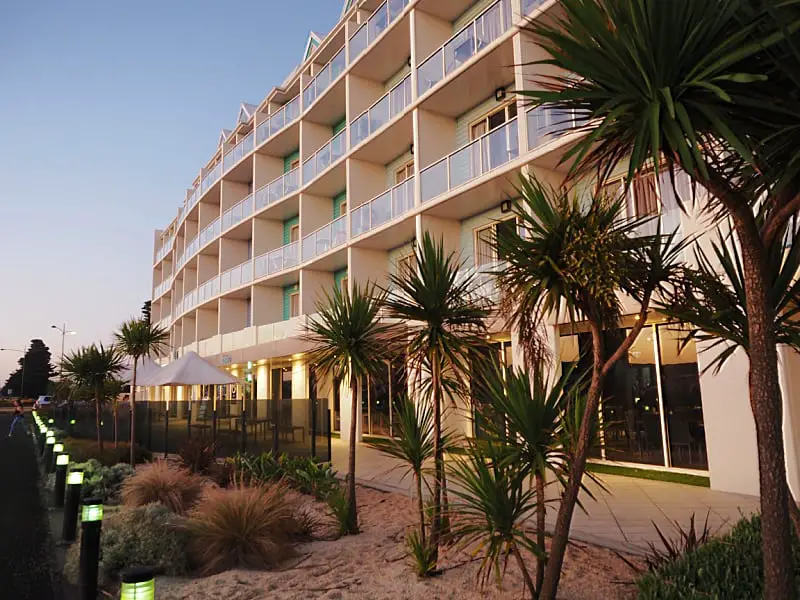 View of the Lady Bay Resort accommodation in Warrnambool at dusk with palm trees and al fresco dining.