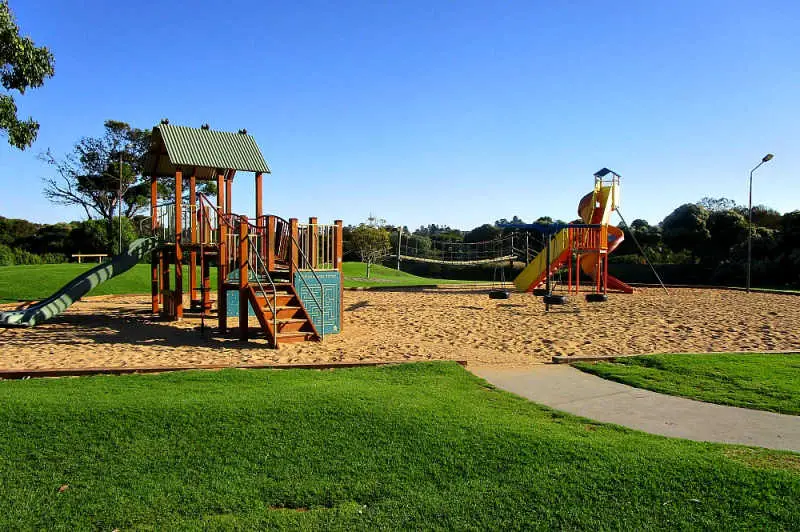 Image of Lake Pertobe Adventure Playground in Warrnambool Victoria with lush green grass and bright blue skies.