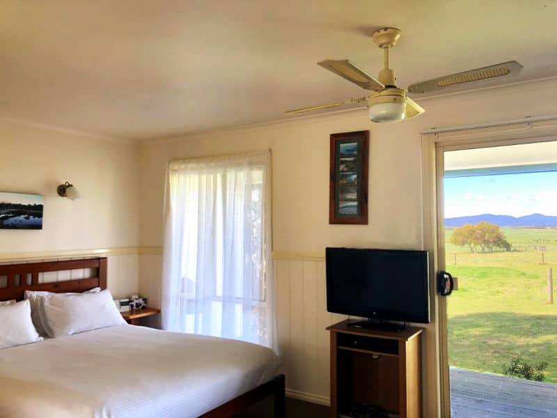 Guest room at Promhills Cabins Yanakie Wilsons Prom accommodation with a bed, TV, and country views.