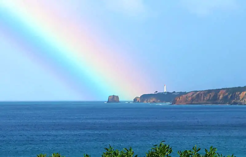 Beautiful rainbow over the ocean and hitting Split Point Lighthouse on the Great Ocean Road in Victoria.