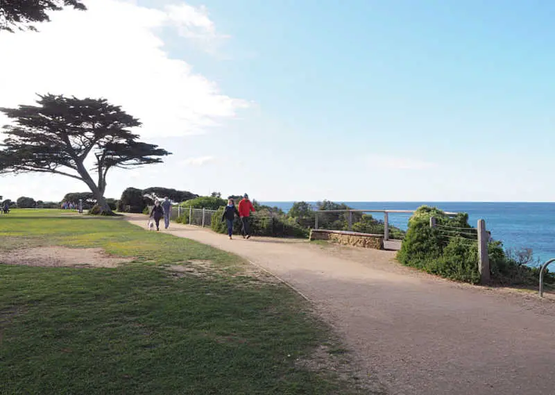 People walking along the Surf Coast Walk in Torquay with trees and views of the ocean.