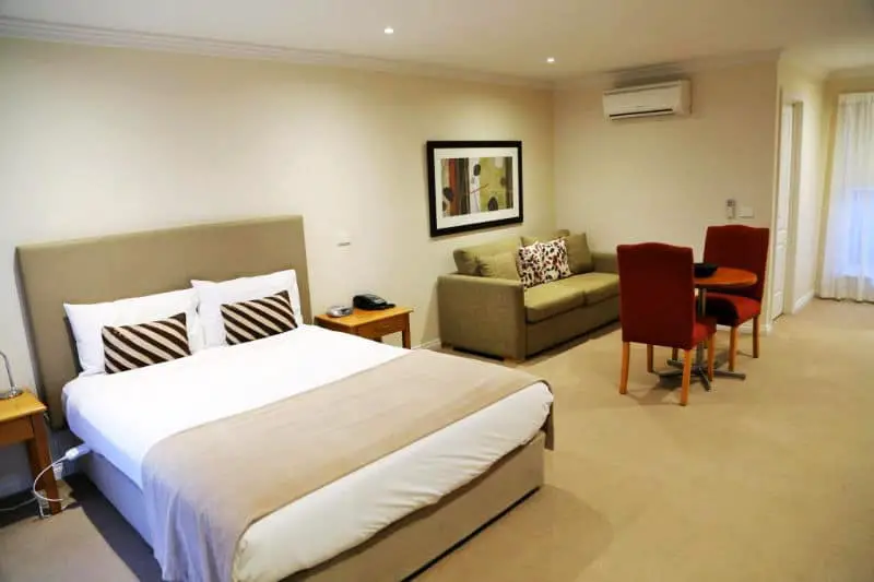 Guest room with double bed, couch, and table and chairs at Allansford Hotel Motel.