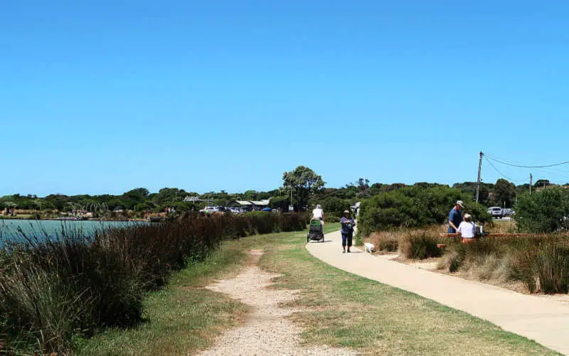People walking beside the river with a dog on the Surf Coast Walk in Anglesea.