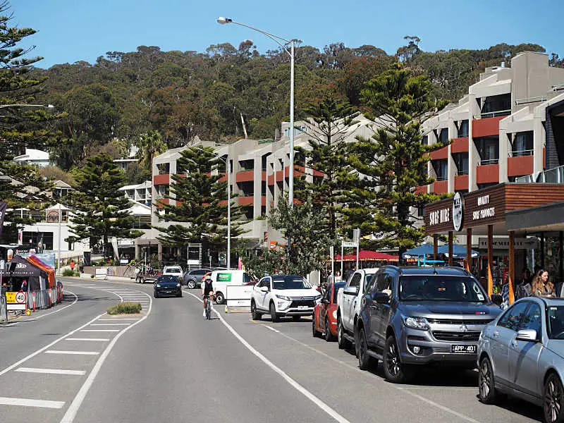 View of the main street in Lorne with cars, trees and a cyclist.