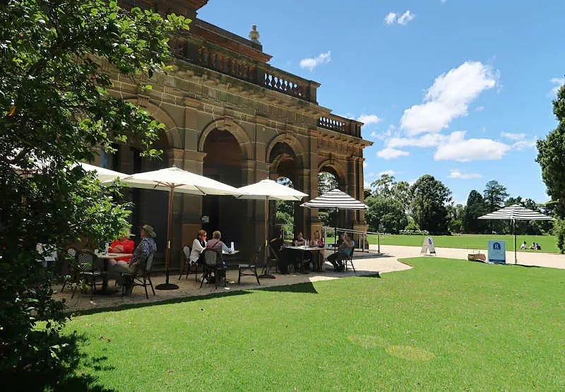 People dining outdoors under umbrellas at Werribee Mansion cafe.