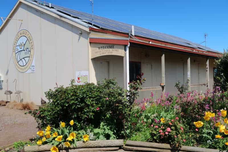 Apostle Whey Cheese entrance with verandah and a garden of pretty flowers.