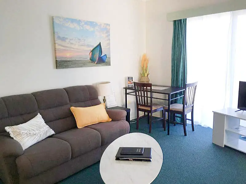 Living space with couch, coffee table, and dining setting at City Heart Motel in Warrnambool Australia.