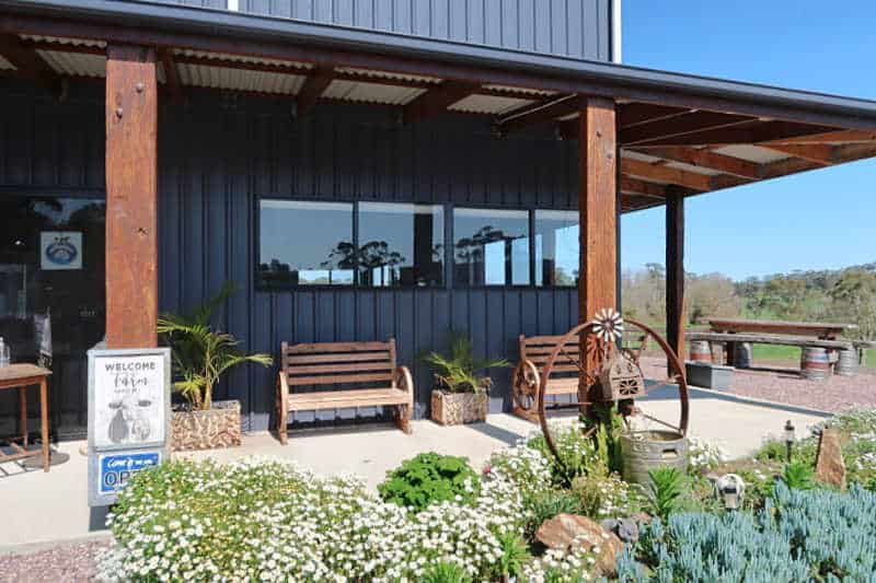 Front entrance to Dairylicious Farm Fudge with verandah, bench seats, and greenery.