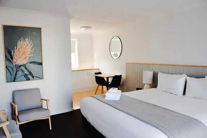 Guest room with double bed, mirror, and table and chairs at Eight Spence one of the best motels in Warrnambool.