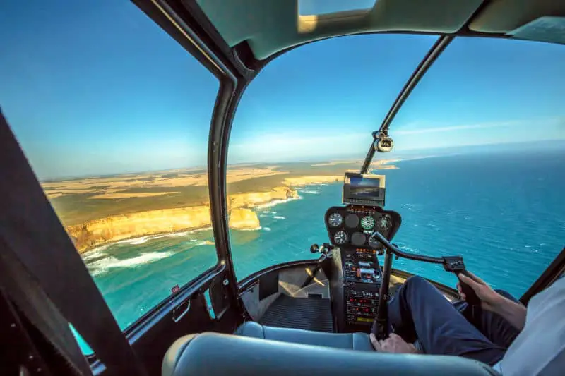Cockpit of a helicopter in the air with views of the Great Ocean Road coastline. 