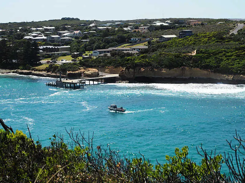 Port Campbell pier with boat approaching and houses in the background.
