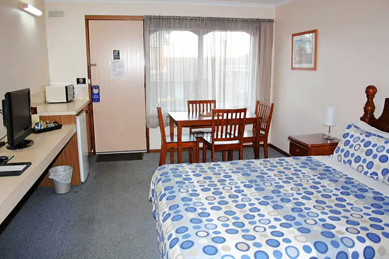 Guest room with bed, table and chairs, a television, and microwave at Raglan Motor Inn Warrnambool.