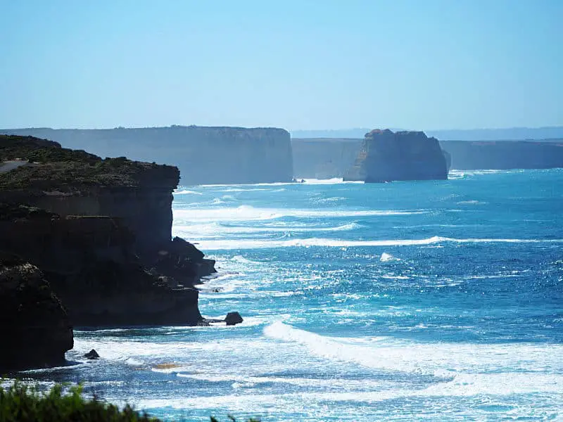 Sentinel Rock surrounded by rugged cliffs and powerful waves with bright blue waves.