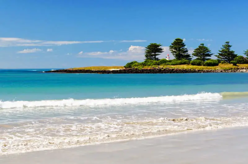 View of Port Fairy Beach with ocean, blue skies and trees.