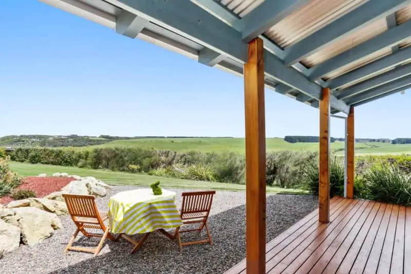 Deck and outdoor table and chairs with country views at Anchors accommodation in Port Campbell.