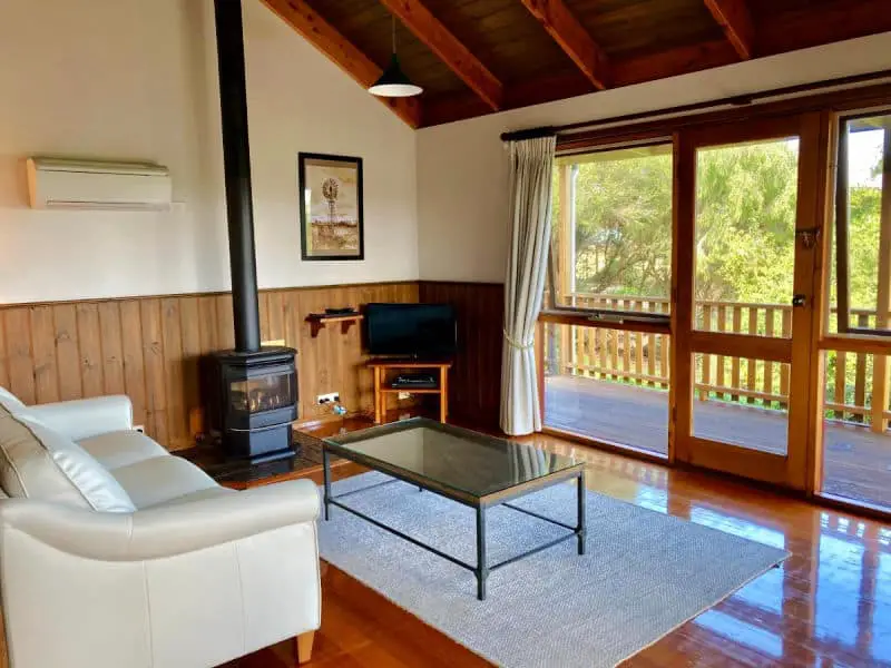 Seating area at Daysy Hill Country Cottages with couches and a fireplace overlooking the garden.