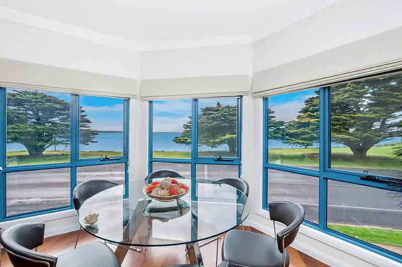 Round table with ocean views from floor to ceiling windows at Seascape Accommodation Portland.