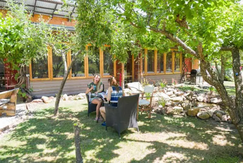 People relaxing in the garden on outdoor furniture at Grampians Eco YHA Halls Gap accommodation.