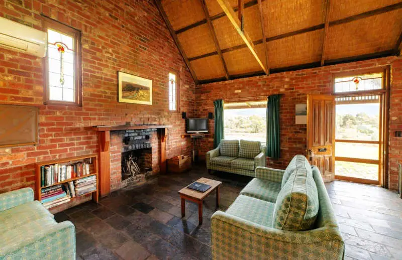 Living area with open fireplace and couches at Grampians Pioneer Cottages.