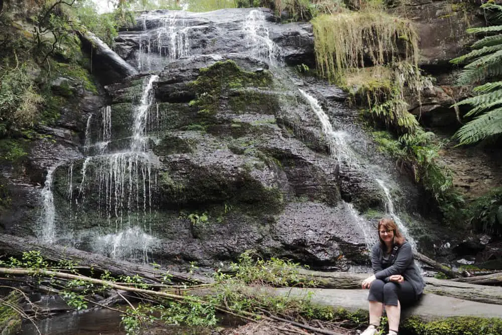 Woman sitting at the base of Henderson Falls in the Otway Ranges.