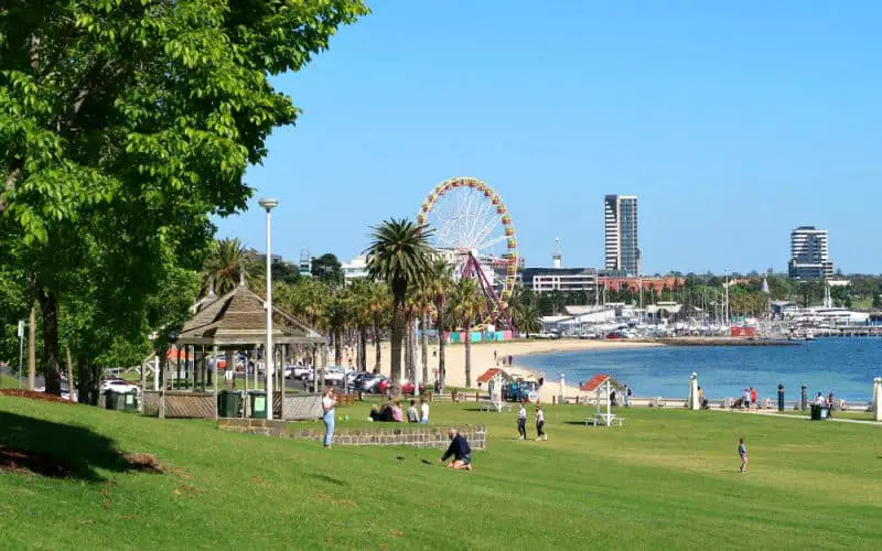 People relaxing at the Geelong Waterfront with a giant ferris wheel in the background.