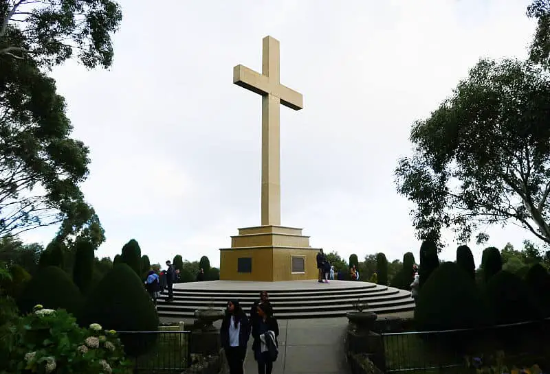 Memorial cross at Mount Macedon with people visiting.