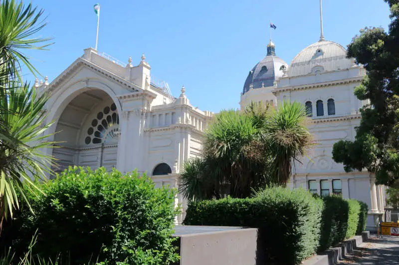 Royal Melbourne Exhibition building with bright blue skies and green trees and hedges.