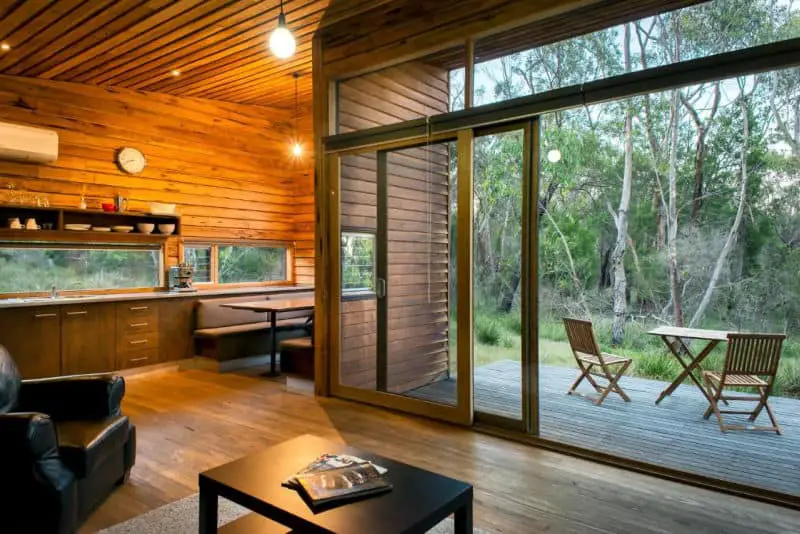 Living area with huge glass doors and deck overlooking bushland at DULC Cabins Halls Gap.