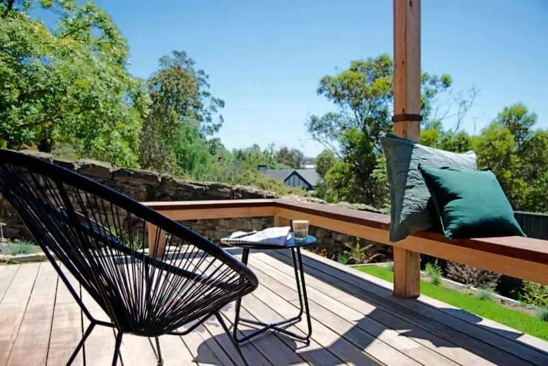 Decking with chair and table surrounded by trees and gardens at 52Views Castlemaine accommodation.
