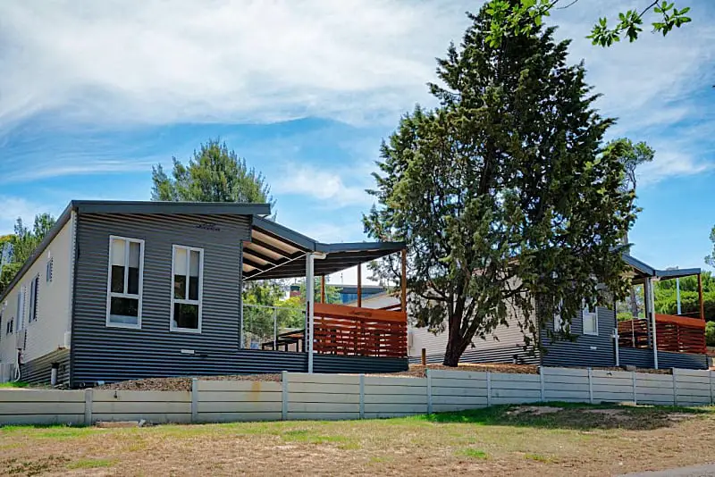 Cabin with deck surrounded by trees at the Big4 Castlemaine Gardens Holiday Park.