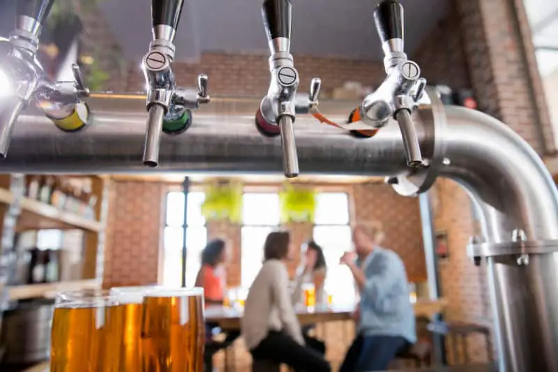 Image of a brewery with beer taps, beer, and people enjoying a drink.