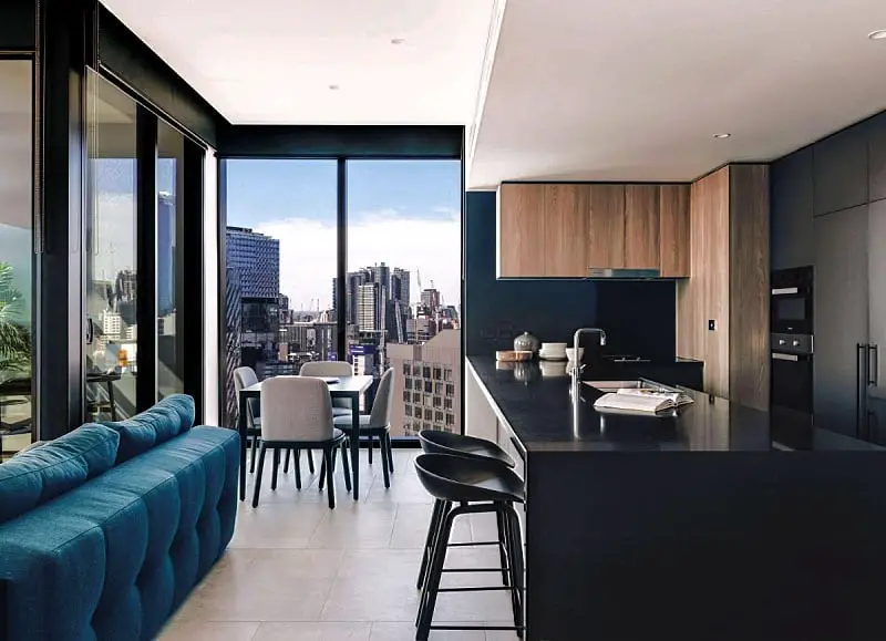 Guest room kitchen and dining area with city views at Novotel Hotel South Wharf. 