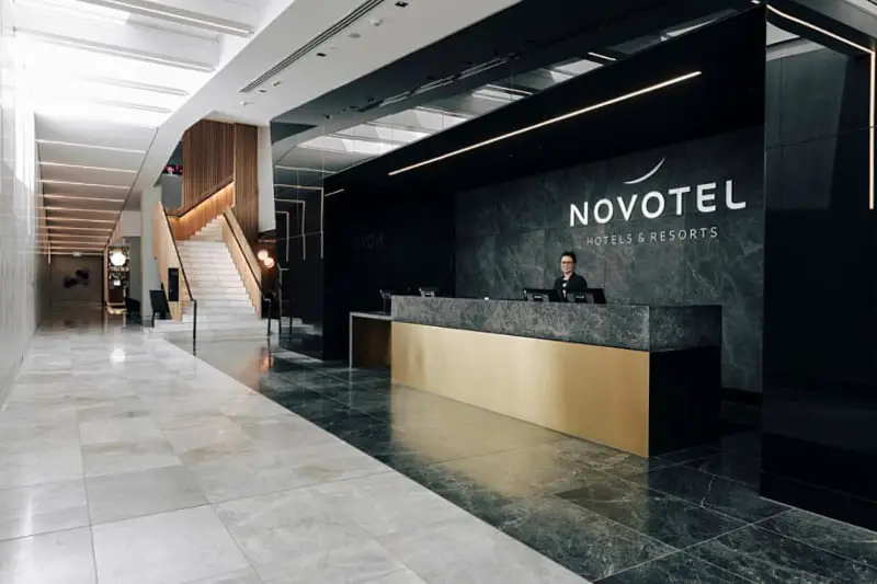 Monochrome reception area with stairs at Novotel South Wharf Hotel.