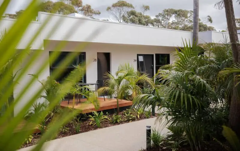 View of the white rooms at Great Ocean Road Resort in Anglesea. There is a small deck and garden out the front of the rooms.