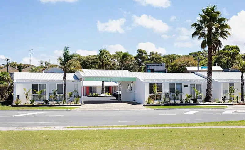View of the bright white Anglesea Riverside Motel with palm trees out the front. A highly rated Anglesea motel.