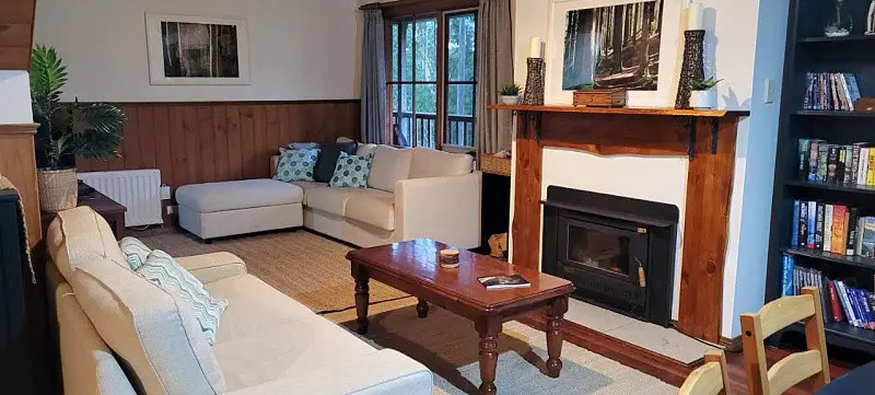 Living room with couches, a coffee table, and wood burner fireplace at Tall Trees Eco Resort Fern Cottage in the Otways.