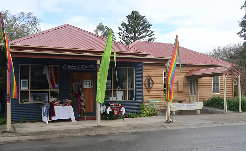 View of the Gellibrand River Gallery Accommodation Otways cottage with brightly coloured flags out the front and craft tables on display. 