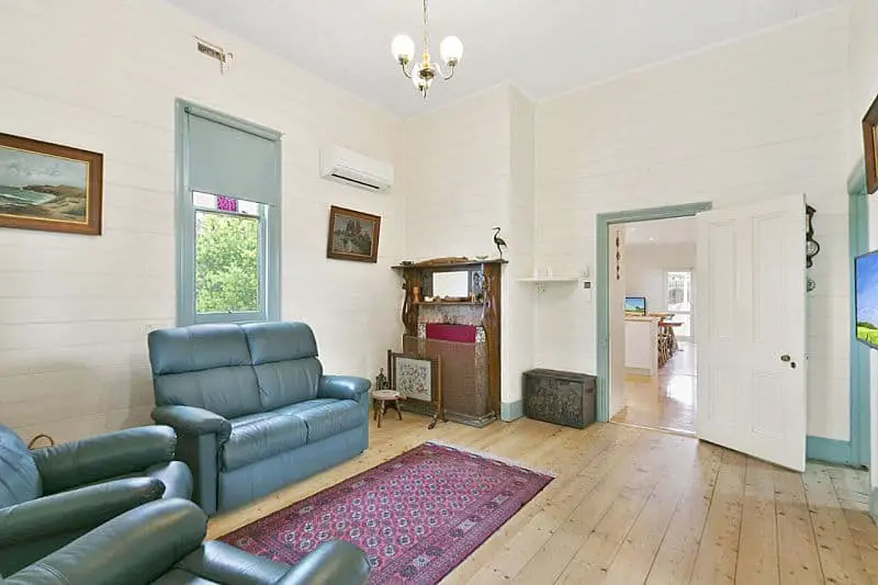 Lounge room with wooden floorboards at couches at Rivernook a historic cottage in Anglesea offering holiday accommodation.