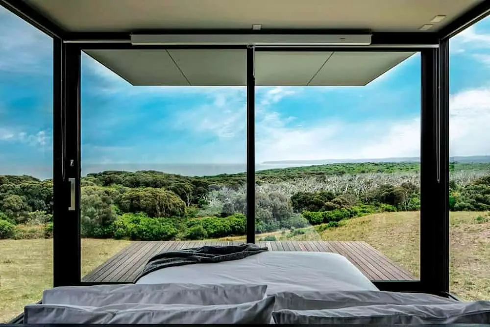 Bedroom surrounded by glass walls with coastal forest views at Sky Pod 1 in Cape Otway. near the Great Ocean Road.
