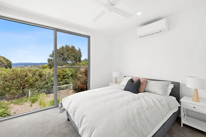 Guest room at Aireys Sunset Beach House with a bed and large window with garden views.