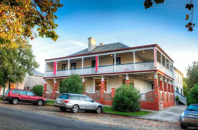Street view of Athelstane House in Queenscliff with wrap around verandah and  parked cars in the street.