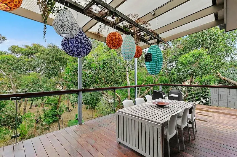 Balcony with colourful lanterns and outdoor setting surrounded by greenery at Bristlebird Aireys Inlet in Victoria Australia.
