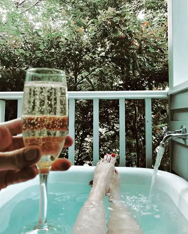 View of a person's legs with painted toe nails while soaking in an outdoor bath and drinking champagne at La Perouse Lorne B&B accommodation.