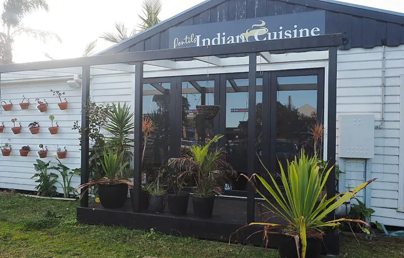 Entrance to Lentils Indian restaurant in Torquay with potted plants and portico.