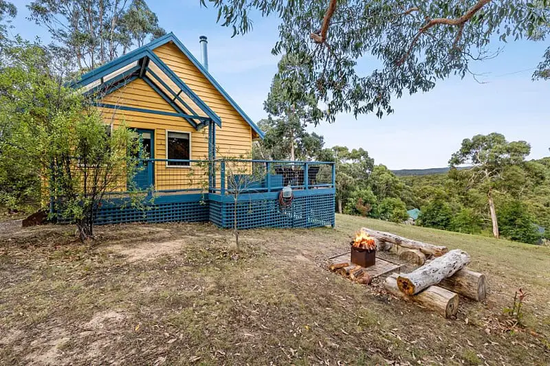 Timber house with balcony overlooking bushland and a fire pit at Lorne Bush House Cottages Eco Retreat.