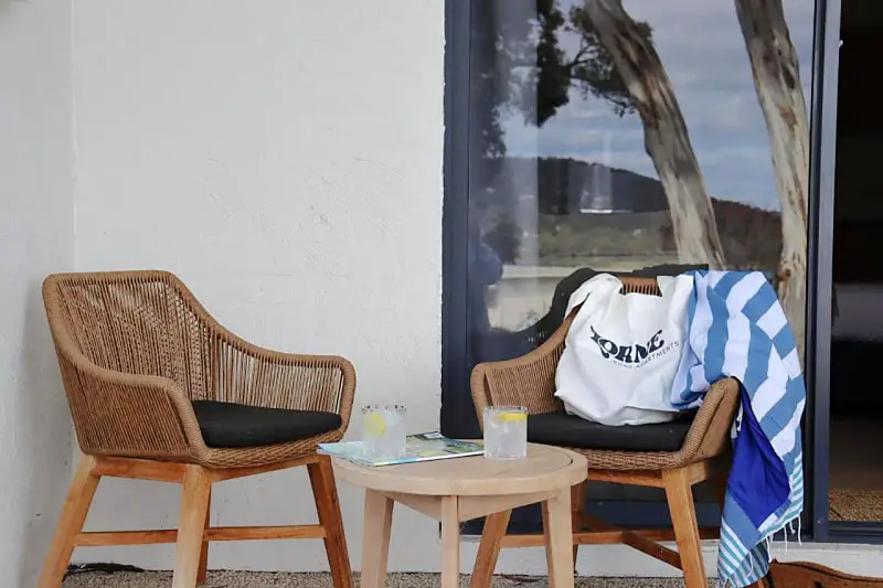 Comfortable chairs with a coffee table and cold drinks on a terrace at Lorne Surf Apartments holiday accommodation.