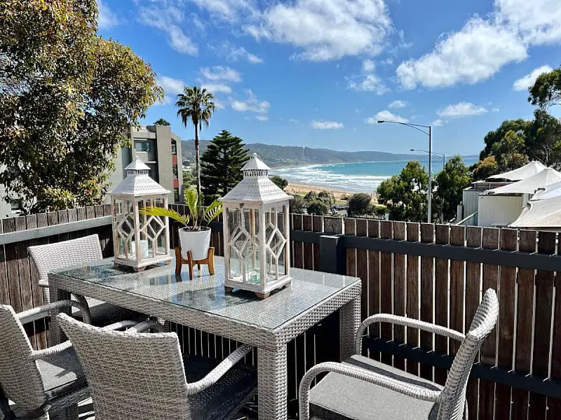 Balcony with outdoor dining and lamps overlooking the ocean at Lorne World accommodation in Lorne Victoria.