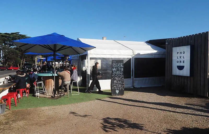 Outdoor dining at Pholklore Torquay restaurant with umbrellas and enclosed verandah.